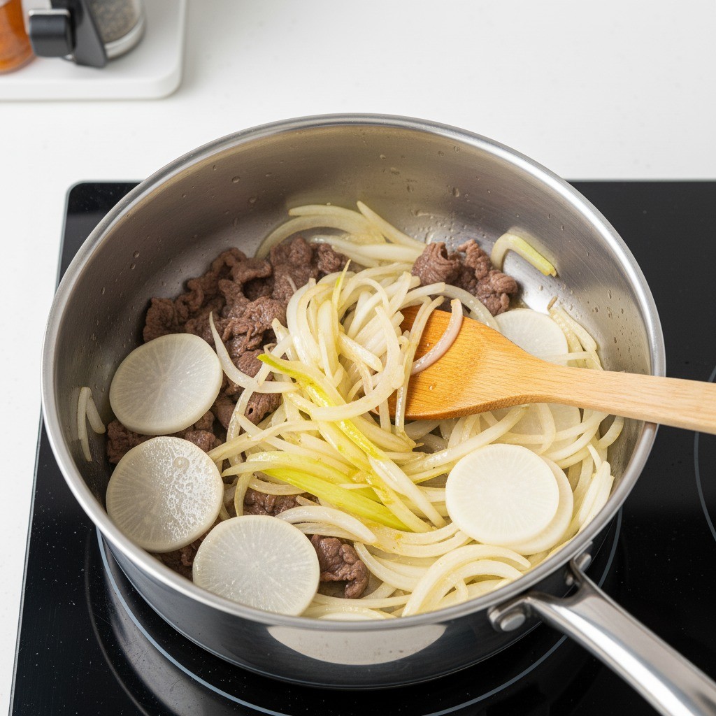 볶던 소고기에 무와 양파를 넣고 함께 볶는 모습
