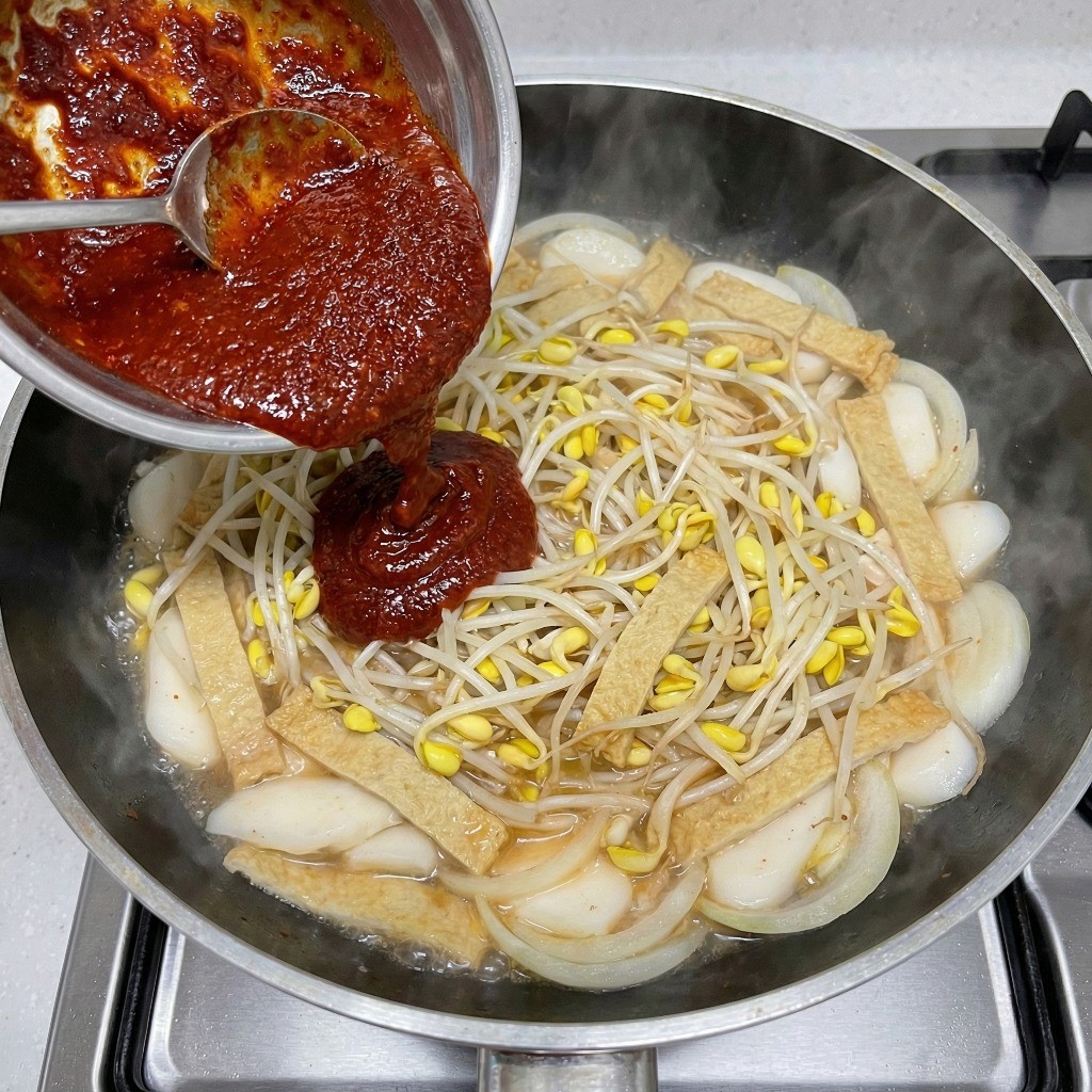 양념장 투하: 숨 죽은 콩나물에 매콤한 양념 섞기