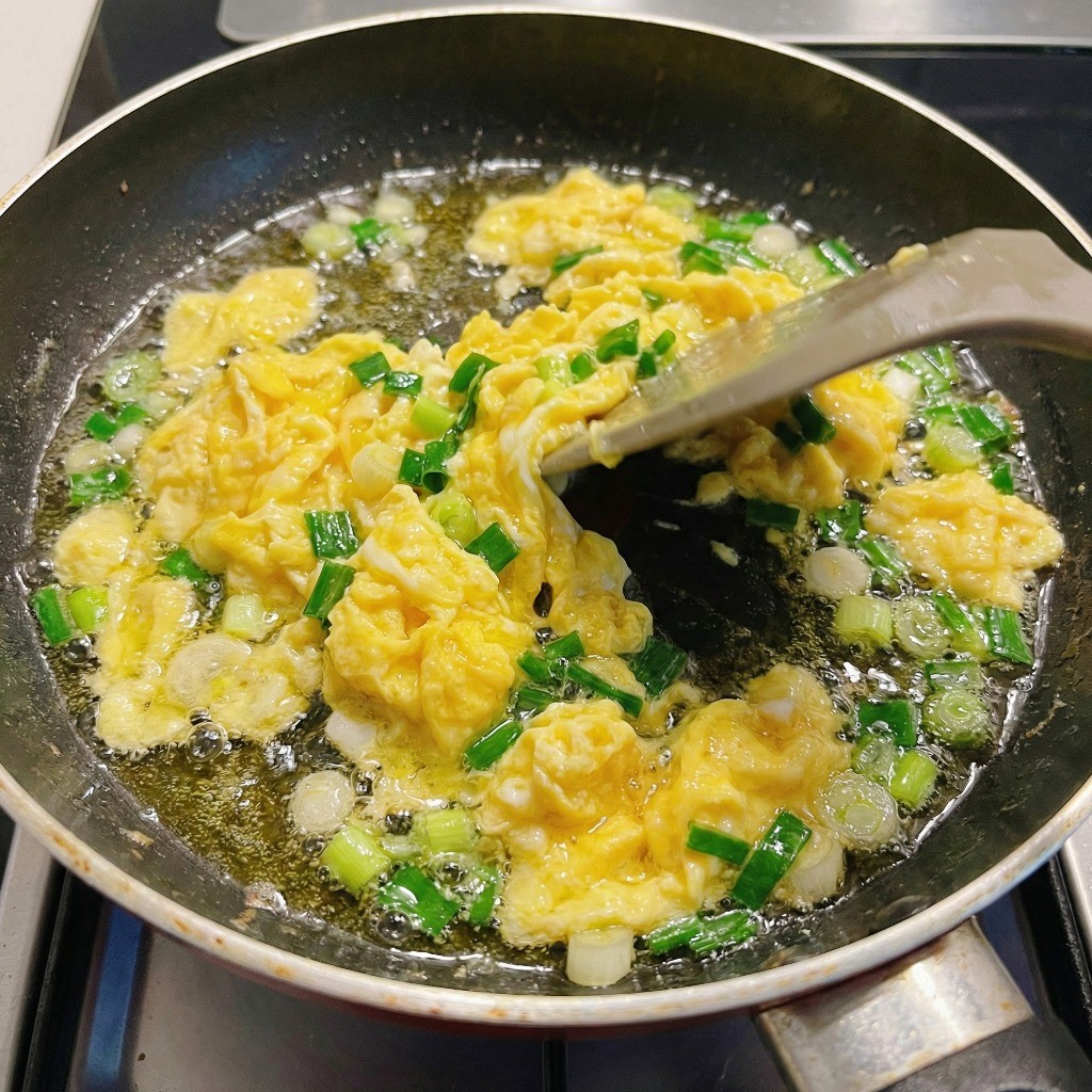 프라이팬에 식용유를 두르고 달걀 스크램블과 대파를 볶아 파기름을 내는 모습
