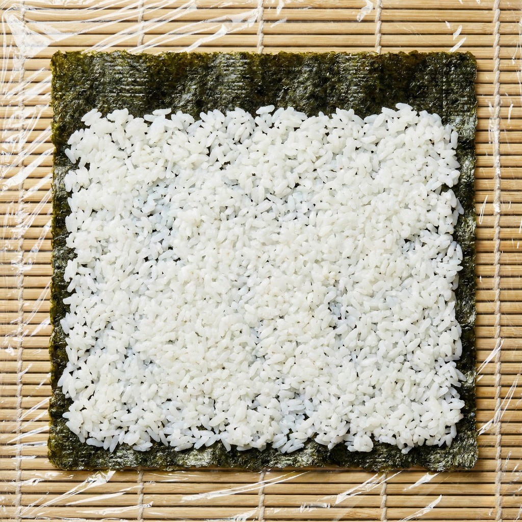 누드 김밥 만들기 비법: 김 위에 밥을 펴고 랩을 씌워 뒤집어 놓은 상태