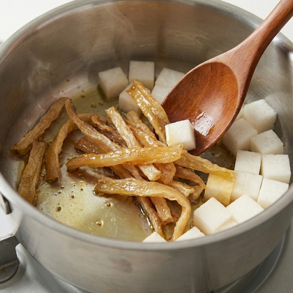 냄비에 참기름을 두르고 북어포를 달달 볶아 고소한 맛을 내는 과정