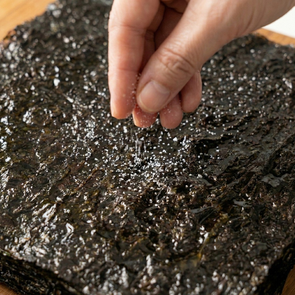 백종원 조미김 만들기 3단계: 들기름을 바른 김밥김 위에 맛소금 솔솔 뿌려 양념하기