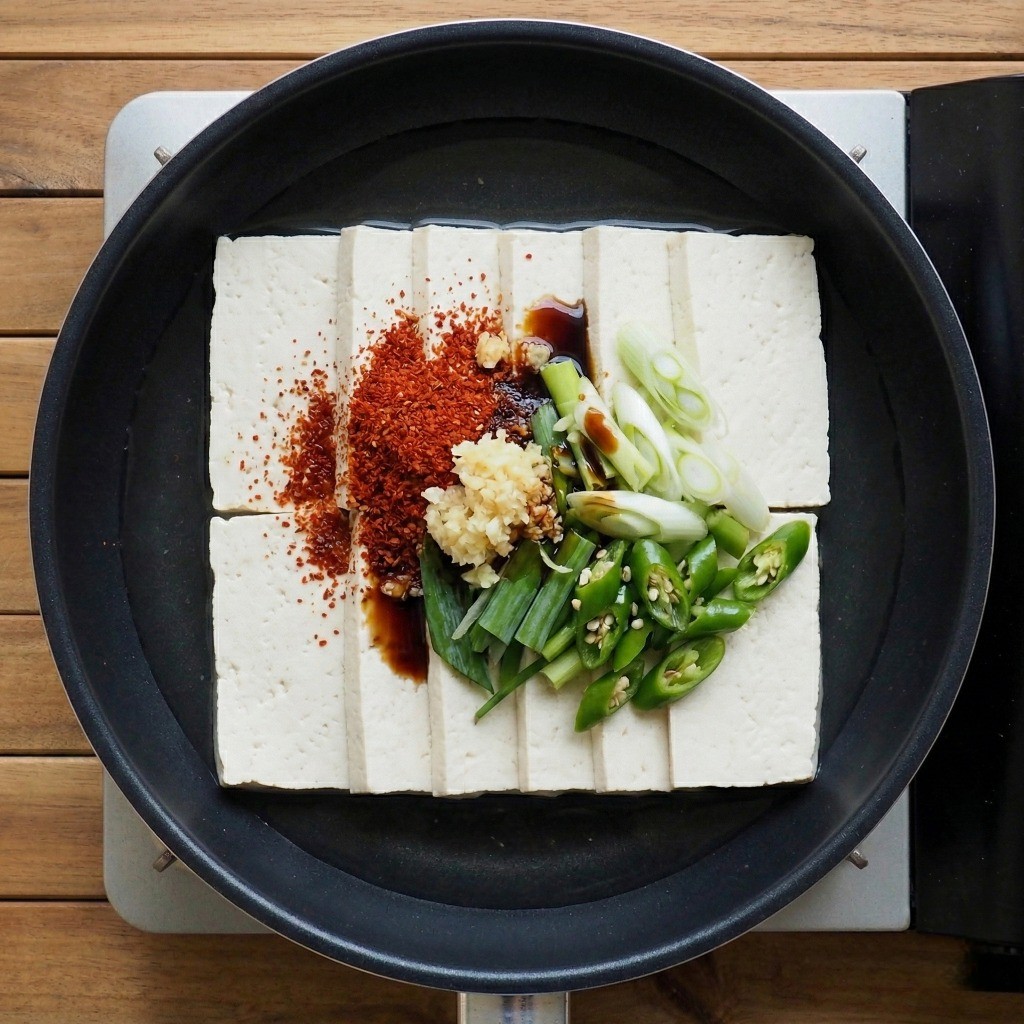 백종원 두부조림 만들기 - 넓은 냄비에 썬 두부를 깔고 새우젓, 고춧가루 등 양념과 물을 부은 모습