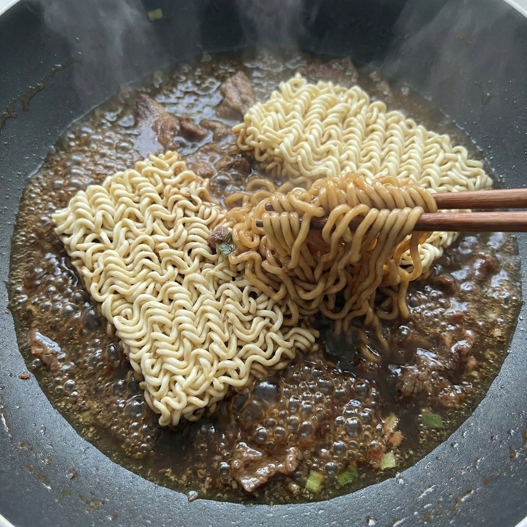 백종원 짜파구리 레시피 4단계: 끓는 양념 국물에 라면 면발을 넣고 쫄깃하게 풀어주는 모습