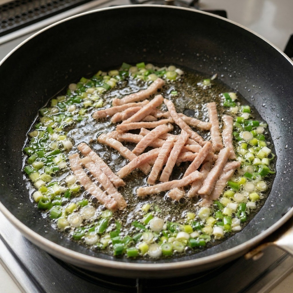 기름을 두른 팬에 대파와 채 썬 돼지고기를 볶아 파기름을 내는 과정