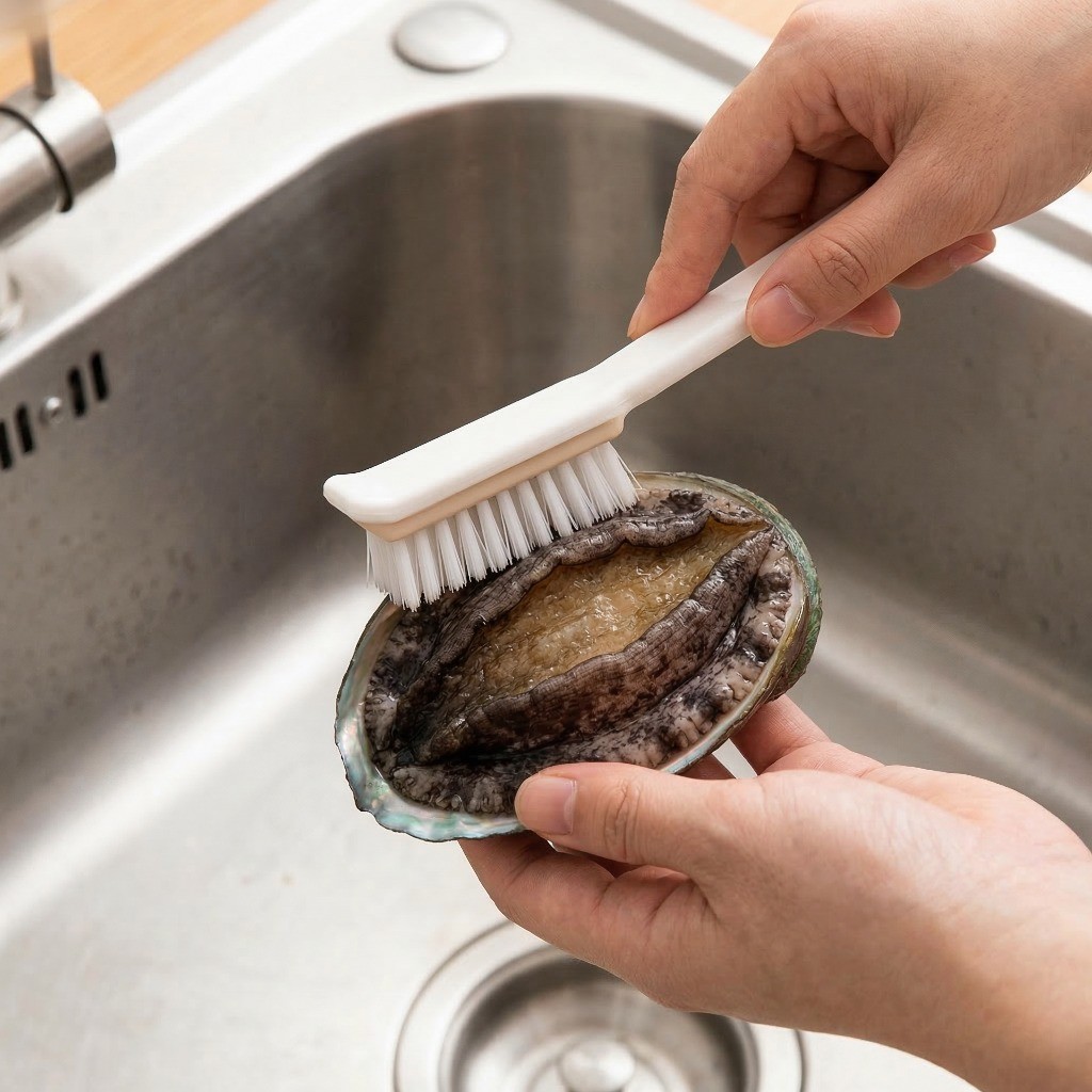 이연복 전복 냉채 레시피 1단계: 주방 솔을 이용해 신선한 전복의 물때를 깨끗하게 손질하는 세척 과정