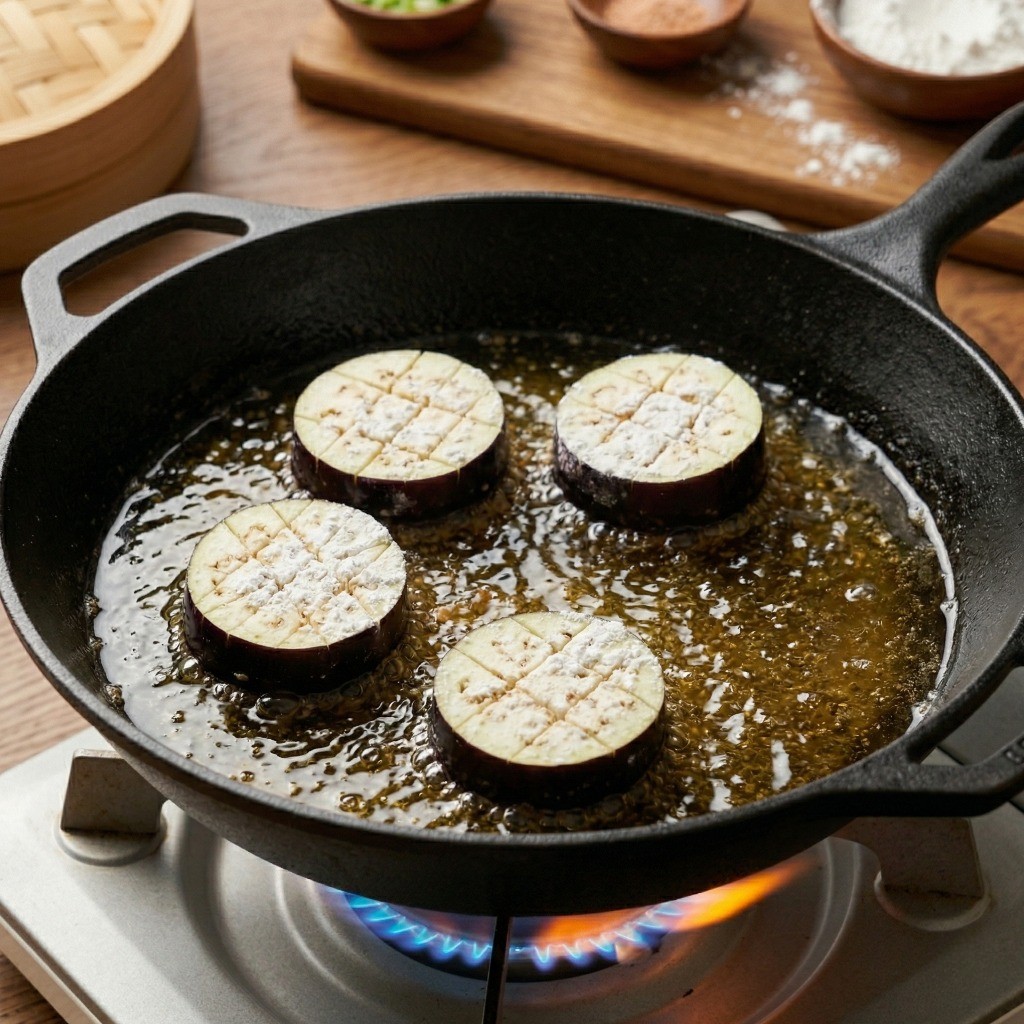 어향가지 만들기 3단계: 칼집 낸 가지에 두부 소시지 속을 채우고 전분 반죽을 입혀 기름에 바삭하게 튀기는 모습