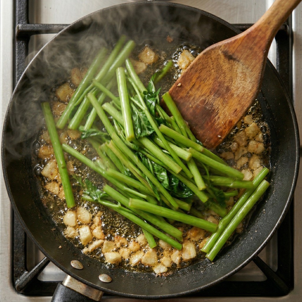 초간단 공심채 볶음 4단계: 마늘 기름에 익는 속도가 느린 공심채 줄기 부분과 소금을 먼저 넣고 볶는 모습