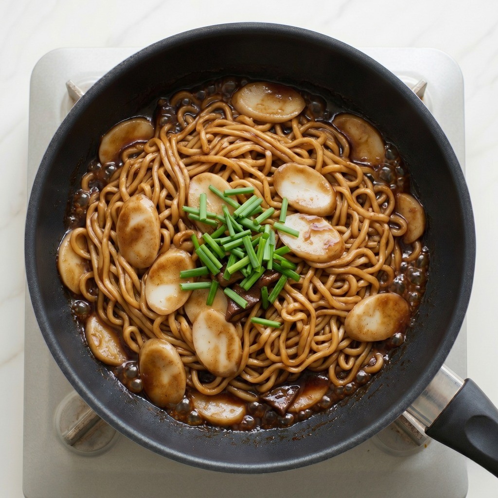 짜장 라볶이 레시피 5단계: 꾸덕하게 졸여진 요리 위에 부추 고명을 얹어 완성한 모습