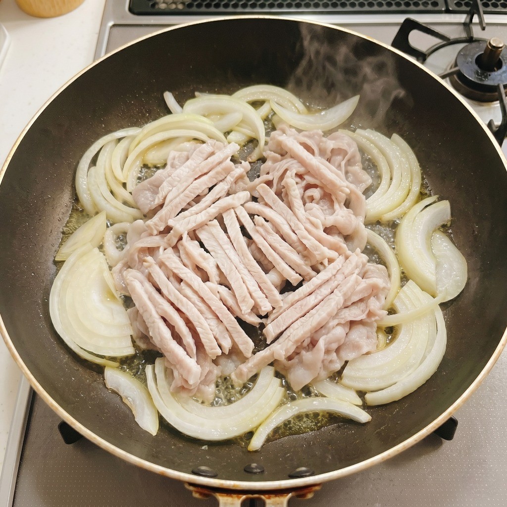 식용유를 두른 프라이팬에 채 썬 양파와 잡채용 돼지고기를 하얗게 익을 때까지 볶는 모습