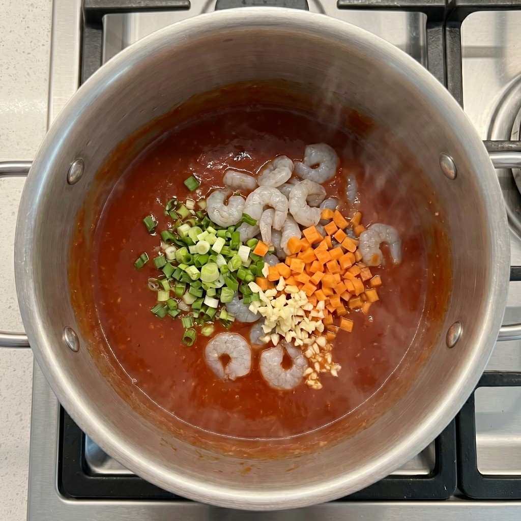 칠리새우 소스에 칵테일 새우, 다진 파, 당근, 마늘을 넣고 끓일 준비를 하는 모습