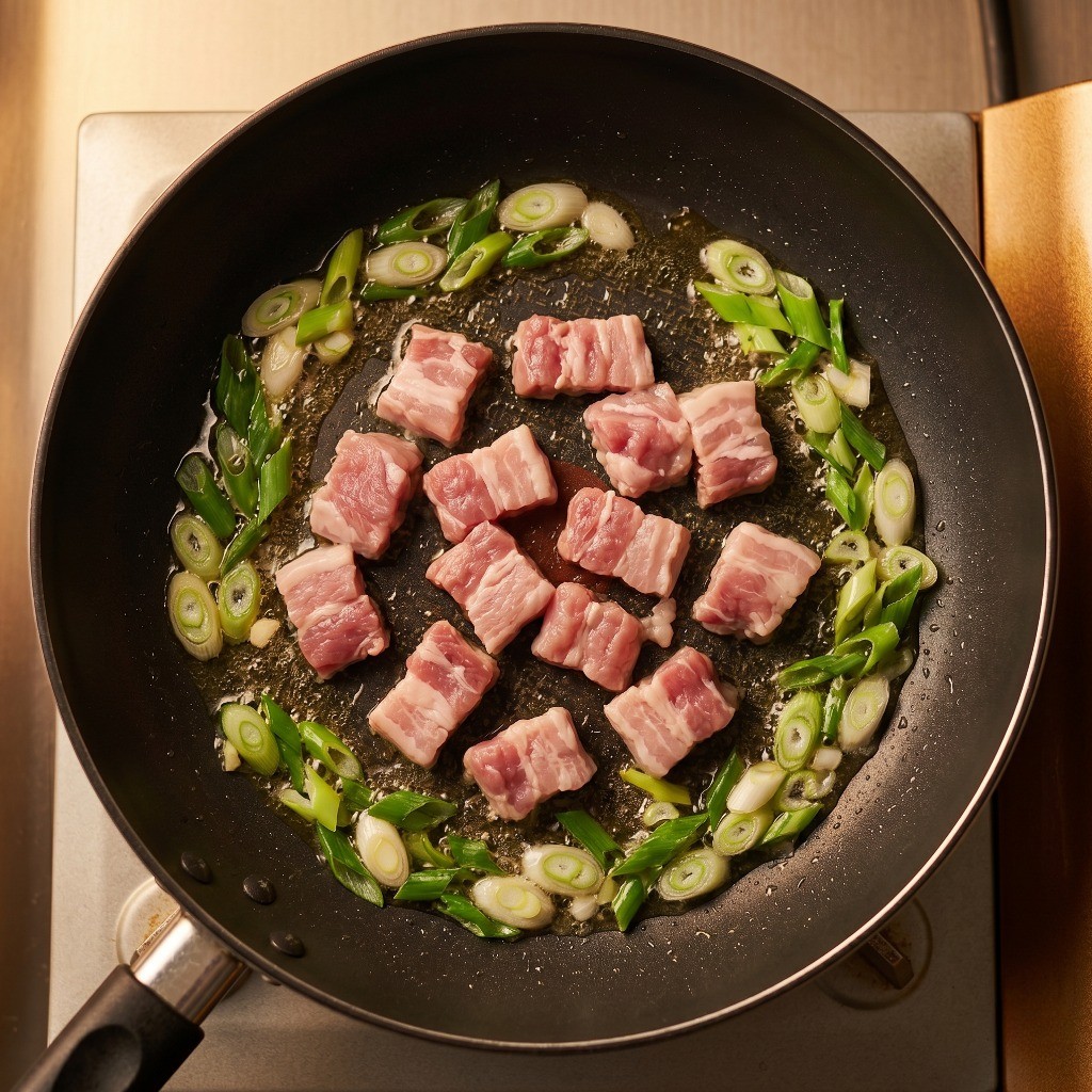 식용유에 대파와 채썬 돼지고기를 넣고 파기름을 내며 볶는 과정