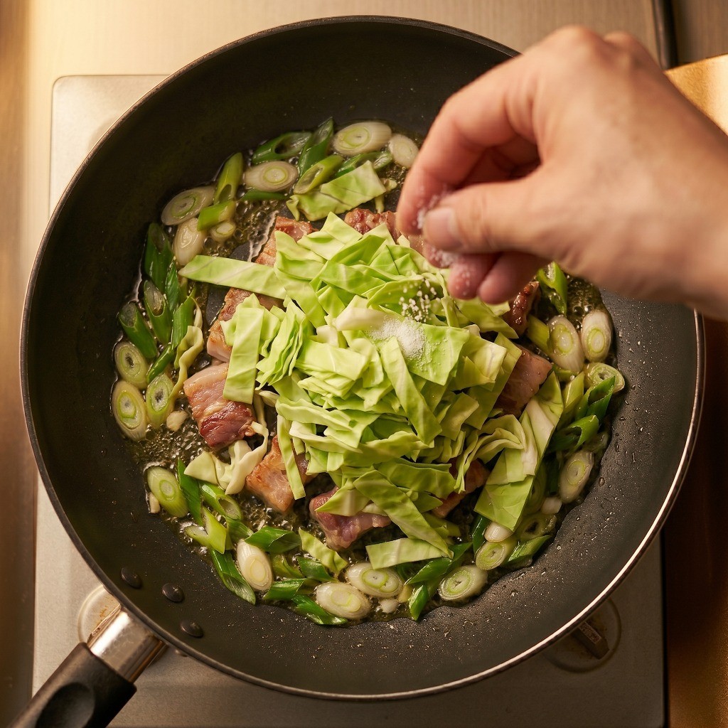 프라이팬에 양배추를 듬뿍 넣고 소금으로 숨을 죽이며 볶는 모습