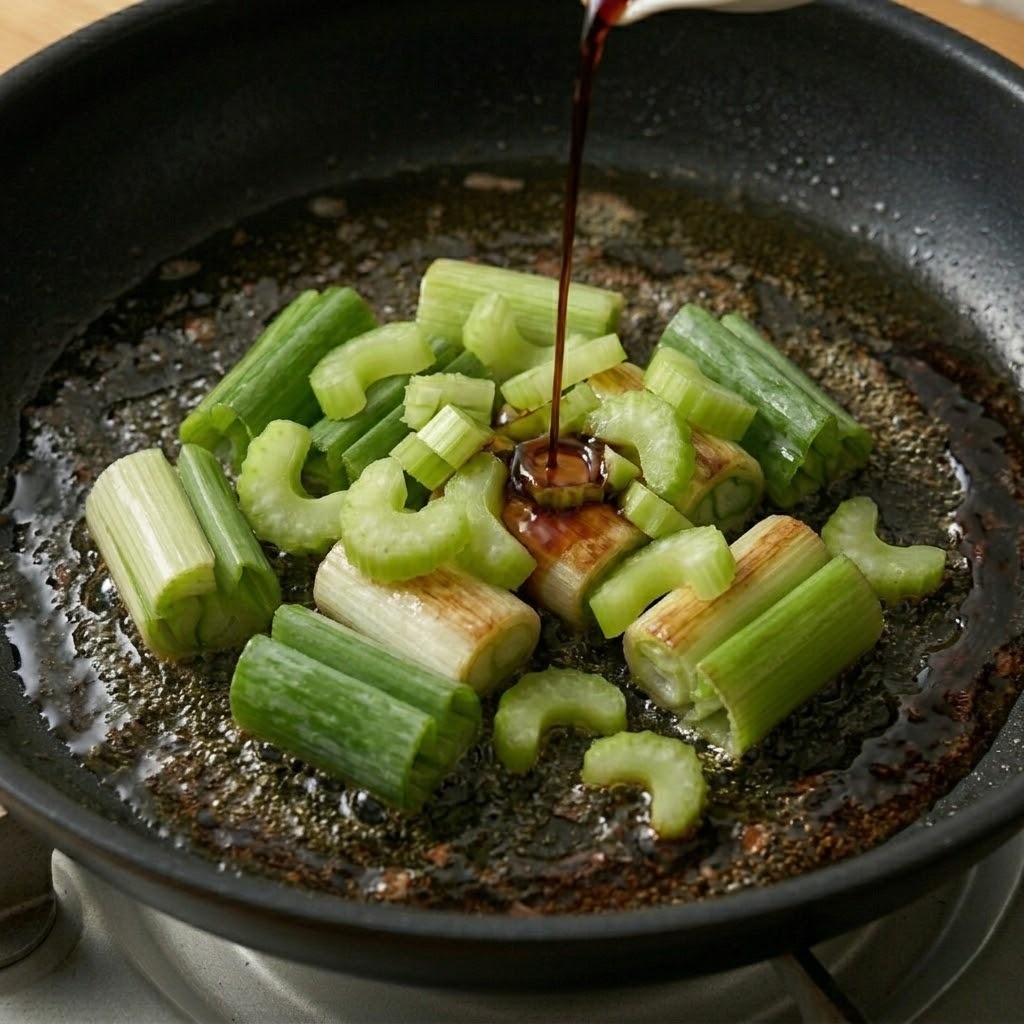 파기름이 끓는 팬에 썰어둔 셀러리를 넣고 볶다가 프라이팬 가장자리로 맛간장을 빙 둘러 중화풍 불향을 입히는 모습